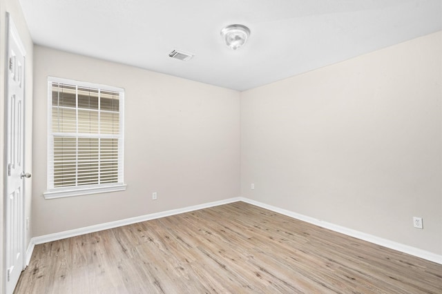 empty room featuring visible vents, baseboards, and light wood finished floors