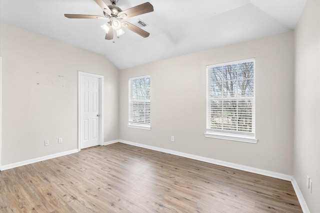 empty room featuring baseboards, visible vents, vaulted ceiling, and light wood-style floors