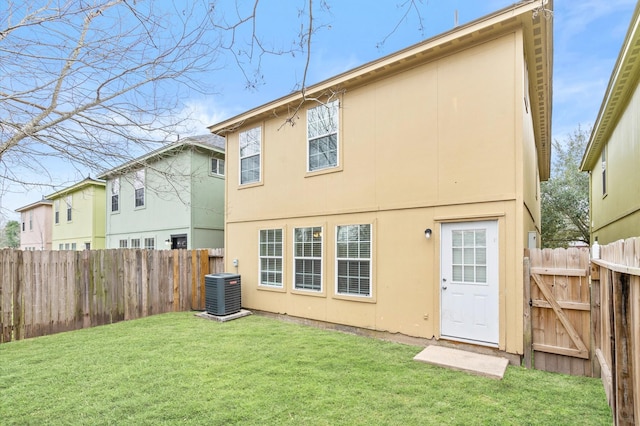 rear view of house with fence, stucco siding, a gate, and a yard