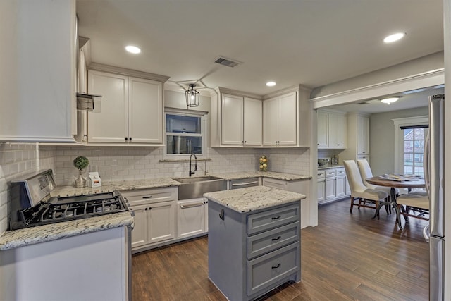 kitchen featuring sink, stainless steel appliances, a center island, light stone countertops, and white cabinets