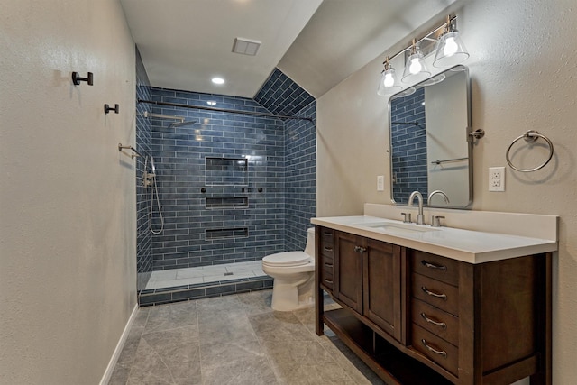 bathroom featuring vanity, a tile shower, and toilet