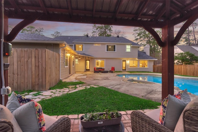 pool at dusk with a lawn and a patio