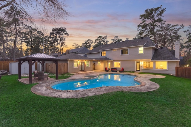 pool at dusk with a gazebo, outdoor lounge area, a lawn, and a patio