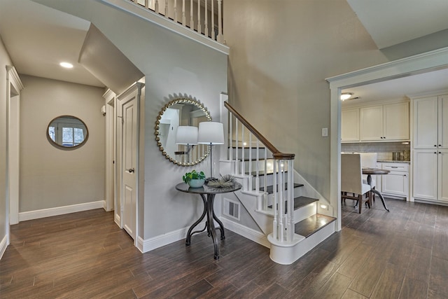 stairway with a towering ceiling and hardwood / wood-style floors