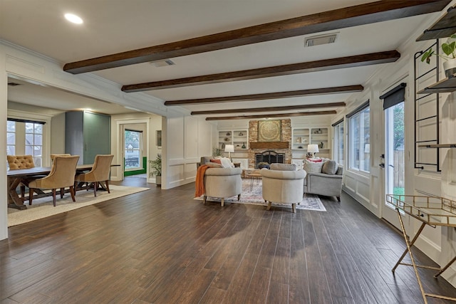 living room featuring dark hardwood / wood-style floors, a large fireplace, beam ceiling, and built in shelves