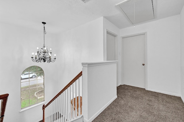 corridor with attic access, dark colored carpet, baseboards, and an upstairs landing