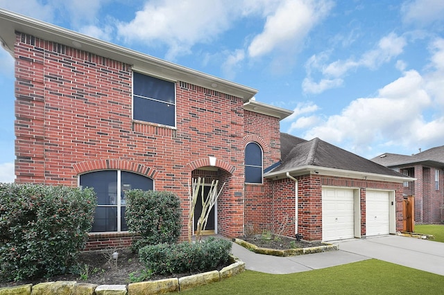 traditional home with brick siding, a shingled roof, concrete driveway, an attached garage, and a front yard