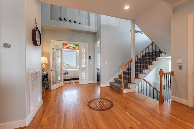 foyer with a towering ceiling and light hardwood / wood-style floors