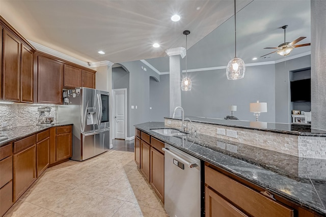 kitchen with stainless steel appliances, sink, dark stone countertops, and decorative light fixtures