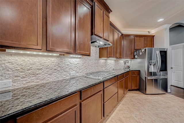 kitchen featuring light tile patterned flooring, dark stone counters, ornamental molding, stainless steel appliances, and decorative backsplash