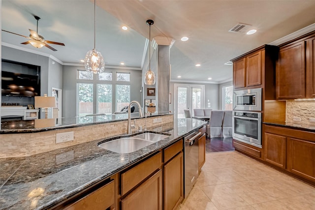 kitchen with pendant lighting, sink, decorative backsplash, ornamental molding, and stainless steel appliances