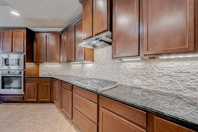 kitchen featuring tasteful backsplash, appliances with stainless steel finishes, light tile patterned floors, and dark stone countertops