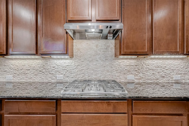 kitchen with dark stone countertops, ventilation hood, tasteful backsplash, and stainless steel gas stovetop