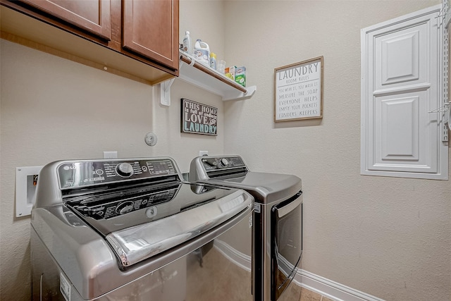 clothes washing area with separate washer and dryer and cabinets