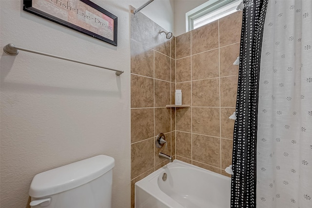 bathroom featuring tiled shower / bath combo and toilet