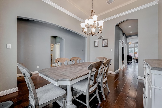 dining area with crown molding, ceiling fan with notable chandelier, and dark wood-type flooring