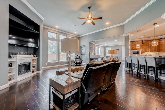 living room with dark wood-type flooring, ceiling fan, and ornamental molding