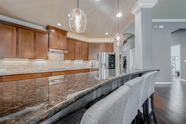 kitchen with crown molding, tasteful backsplash, hanging light fixtures, appliances with stainless steel finishes, and a kitchen breakfast bar