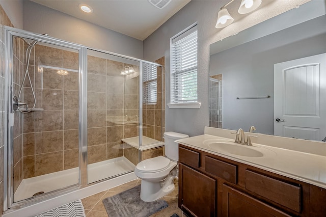 bathroom with vanity, toilet, a shower with door, and tile patterned flooring