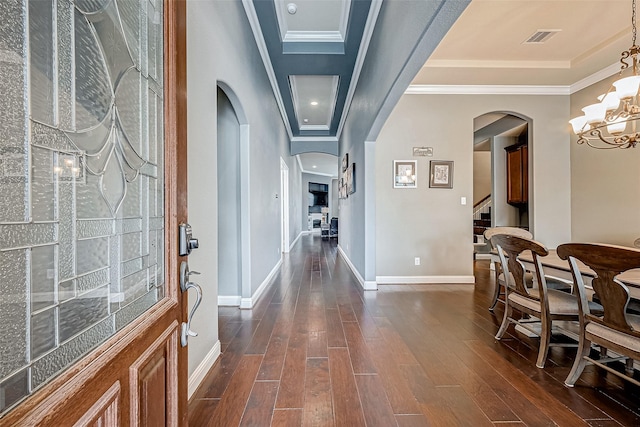 hallway with crown molding, dark wood-type flooring, and a notable chandelier