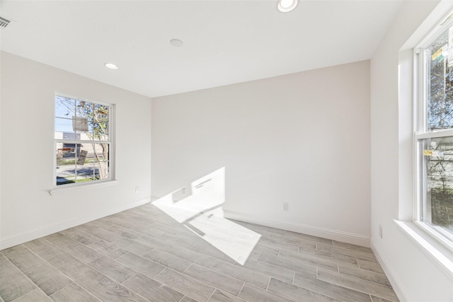 empty room featuring wood tiled floor, visible vents, baseboards, and a wealth of natural light