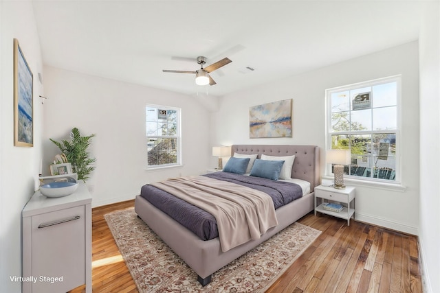 bedroom with light wood-type flooring, a ceiling fan, and baseboards