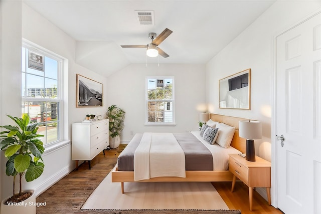 bedroom with dark wood-type flooring, visible vents, vaulted ceiling, and baseboards