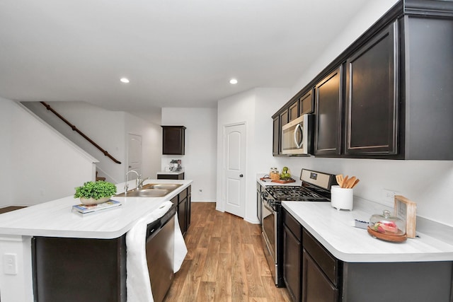 kitchen featuring a kitchen island with sink, sink, light hardwood / wood-style floors, and appliances with stainless steel finishes