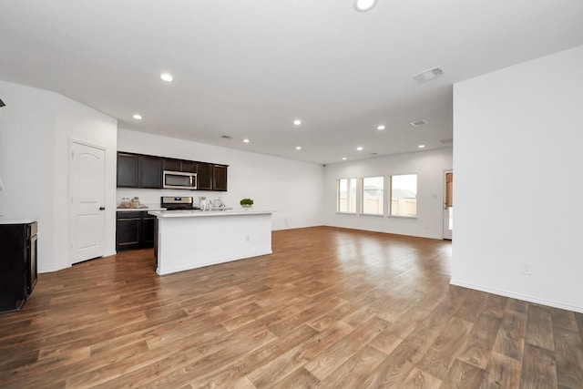 kitchen featuring light hardwood / wood-style floors, dark brown cabinets, stainless steel appliances, and an island with sink