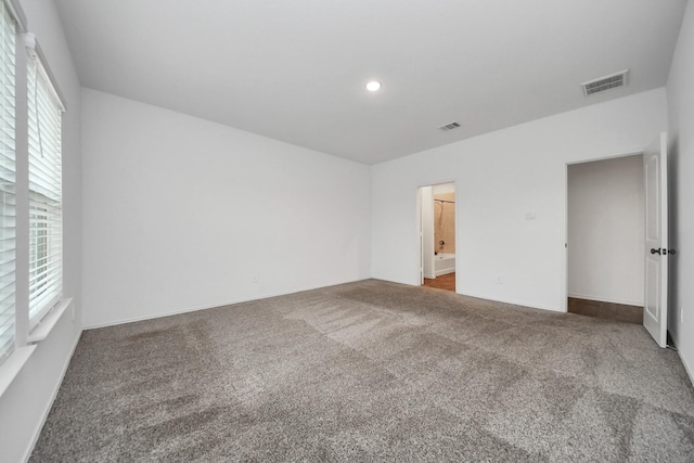 unfurnished bedroom featuring dark carpet and ensuite bathroom