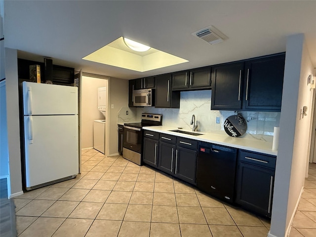 kitchen featuring sink, stainless steel appliances, stacked washer / dryer, tasteful backsplash, and light tile patterned flooring