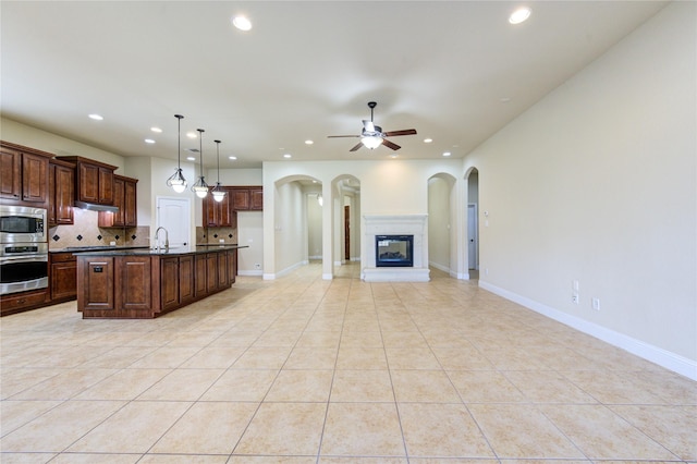 kitchen featuring pendant lighting, sink, stainless steel appliances, an island with sink, and decorative backsplash