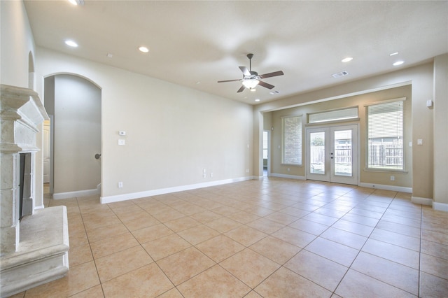 spare room with a high end fireplace, light tile patterned floors, ceiling fan, and french doors