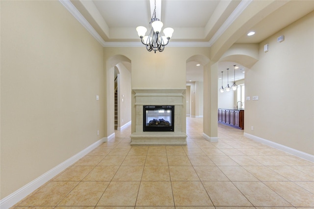 unfurnished living room featuring an inviting chandelier, light tile patterned floors, a raised ceiling, and a multi sided fireplace