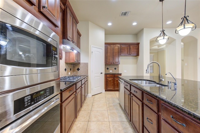 kitchen with decorative light fixtures, sink, dark stone countertops, decorative backsplash, and light tile patterned floors