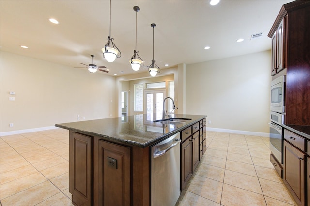 kitchen with sink, a center island with sink, stainless steel appliances, light tile patterned flooring, and french doors