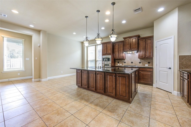 kitchen featuring pendant lighting, an island with sink, backsplash, light tile patterned floors, and stainless steel appliances