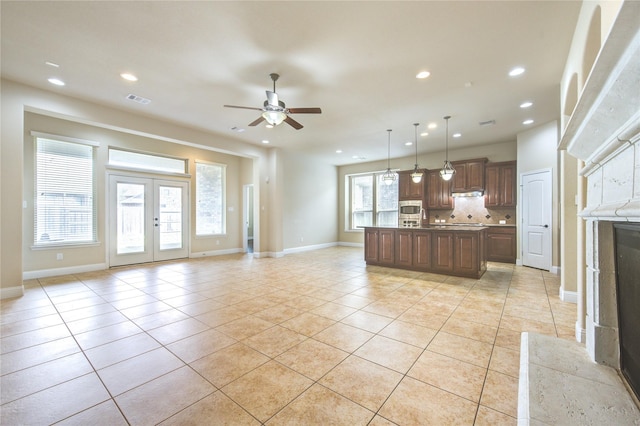 kitchen featuring tasteful backsplash, hanging light fixtures, a center island with sink, and light tile patterned floors