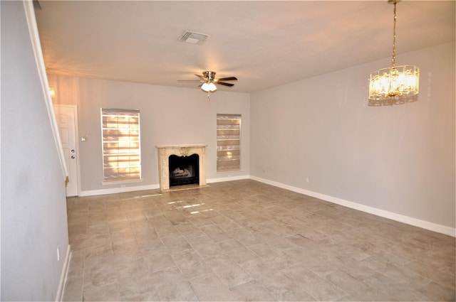 unfurnished living room with ceiling fan with notable chandelier and a premium fireplace