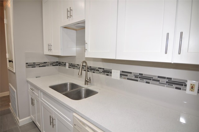 kitchen featuring white cabinetry, light stone countertops, sink, and backsplash