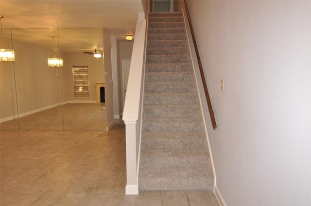 staircase featuring tile patterned flooring and ceiling fan with notable chandelier