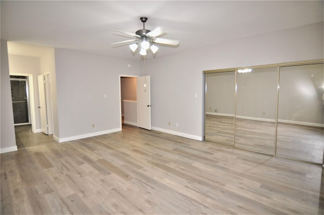 unfurnished bedroom featuring ceiling fan, ensuite bathroom, a closet, and light hardwood / wood-style flooring