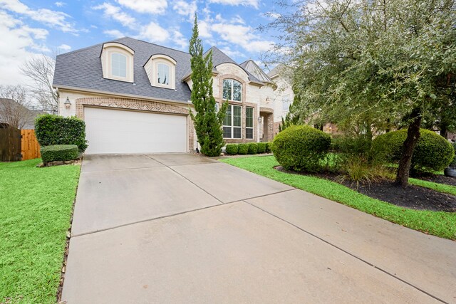 french country style house with brick siding, a shingled roof, fence, driveway, and a front yard