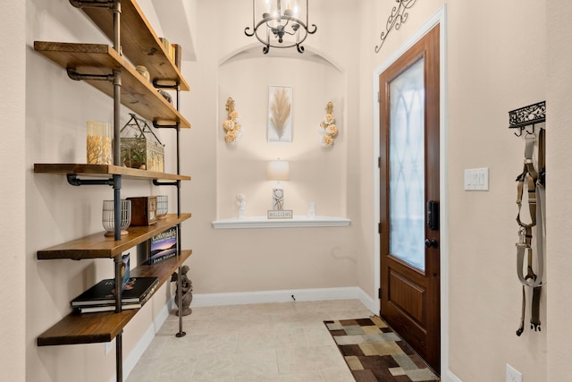 foyer entrance with a notable chandelier, baseboards, and tile patterned floors