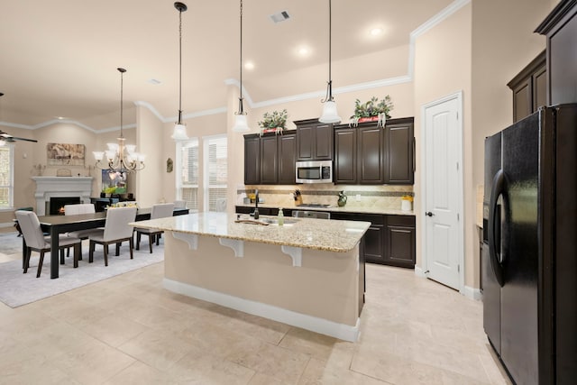 kitchen with a fireplace, black fridge with ice dispenser, visible vents, tasteful backsplash, and stainless steel microwave