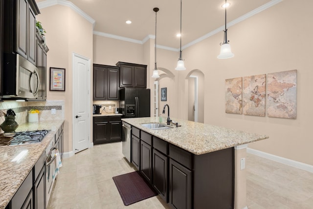 kitchen featuring arched walkways, appliances with stainless steel finishes, ornamental molding, a kitchen island with sink, and a sink