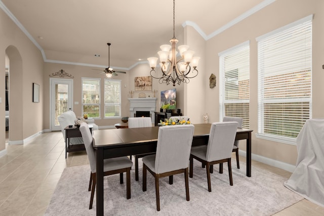 dining space with arched walkways, light tile patterned floors, ornamental molding, a warm lit fireplace, and baseboards