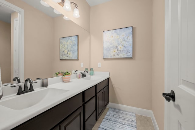 full bath with double vanity, tile patterned flooring, a sink, and baseboards