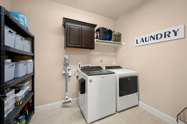 washroom with baseboards, light tile patterned flooring, cabinet space, and washer and dryer