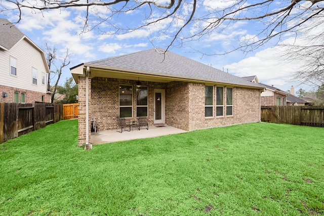 rear view of property featuring a fenced backyard, a lawn, a ceiling fan, and brick siding